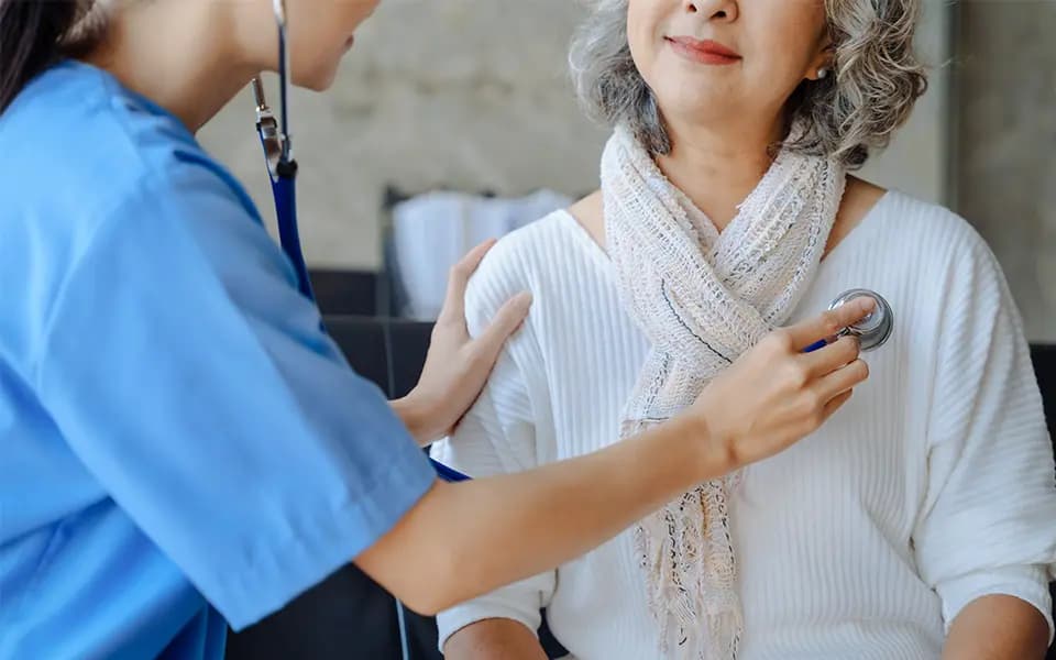 Doctor with a stethoscope examining the lungs of an elderly patient