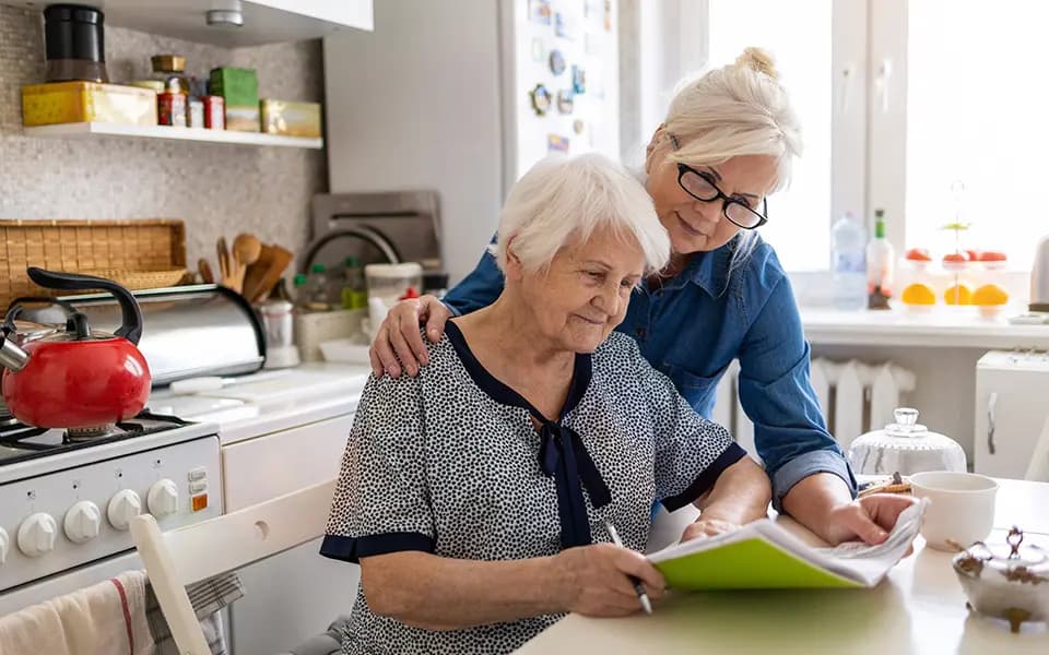 Mature woman helping elderly mother with paperwork