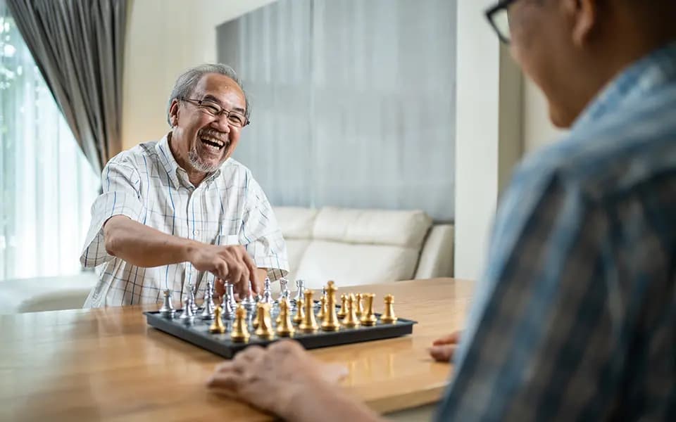 Older friends playing chess and smiling