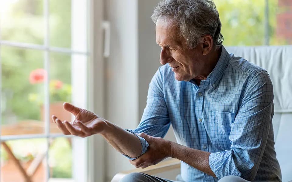 Man holding elbow in discomfort