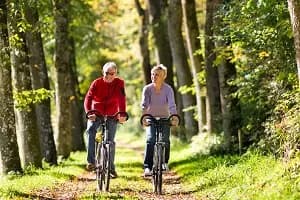 senior couple riding bikes on trail in the woods
