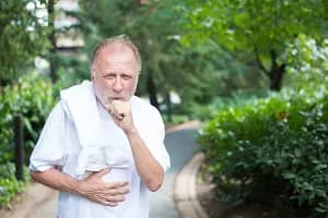 senior man coughing while exercising outside