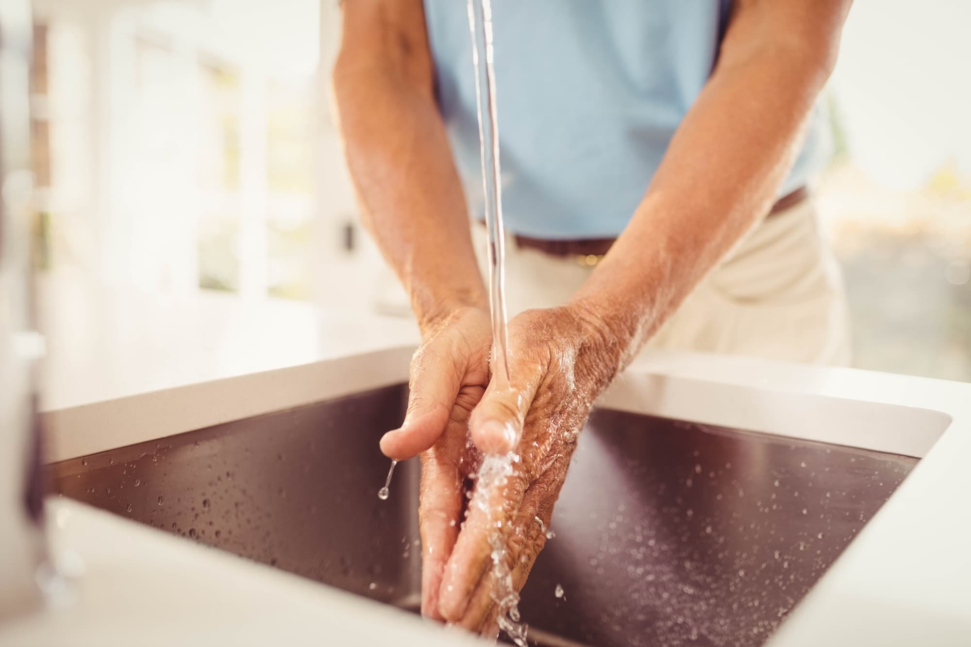 A man leaning over a sink washing his hands under running water