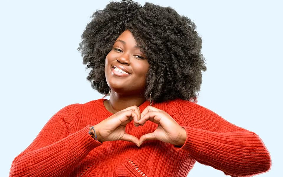 Smiling woman showing heart-shape symbol with hands