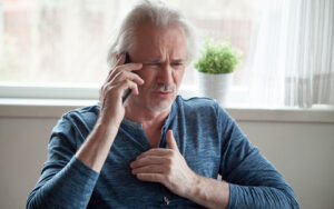Stressed senior mature man feeling chest pain talking on phone. Click to learn about the subtle signs of a heart attack.